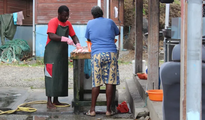 Femme entrain de nettoyer du poisson